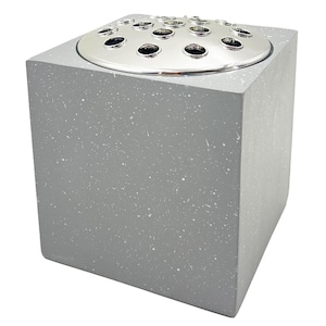 May include: A square grey concrete vase with a silver metal top. The top has multiple holes for holding flowers.