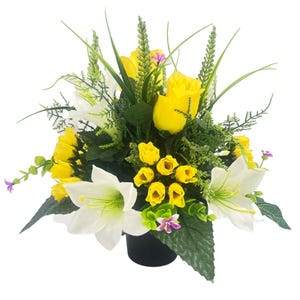 May include: A floral arrangement with yellow roses and white lilies, complemented by green foliage and small purple flowers. The flowers are in a black pot, creating a vibrant and colourful display.