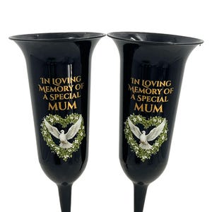 May include: Two black vases with a flared top and a slender base. The vases feature gold text that reads "IN LOVING MEMORY OF A SPECIAL MUM" above a heart-shaped wreath with a white dove in the center.