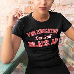 May include: A black t-shirt with red text that reads "PWI Educated But Still Black AF".