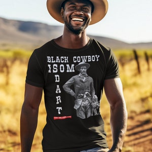 May include: A black t-shirt with a white graphic print of a black cowboy with the text "BLACK COWBOY IS SOME DART THAT MELANIN THO".