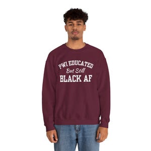 May include: A maroon sweatshirt with white text that reads "PWI Educated But Still Black AF".