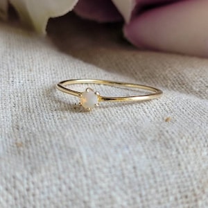 Peut inclure: Une délicate bague en or avec une petite pierre d'opale blanche.