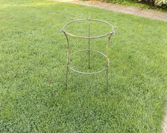 May include: A metal plant support with two circular rings. The support is made of black metal and has a simple design.