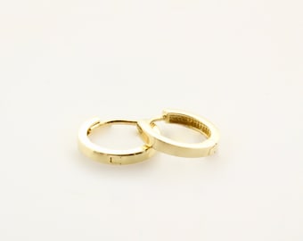 May include: A pair of gold hoop earrings. The earrings are simple and elegant, with a smooth, polished finish.