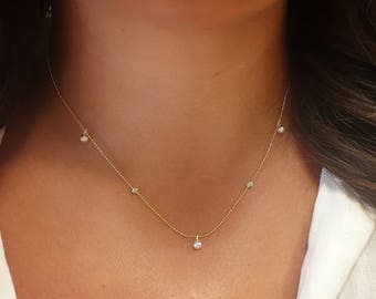 May include: A delicate gold chain necklace with a single pearl pendant and three small diamond accents.