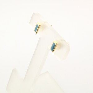 May include: A pair of gold stud earrings with a rectangular blue stone in the center.