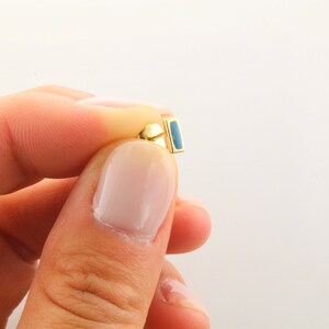 May include: Gold earring with a blue rectangular stone.