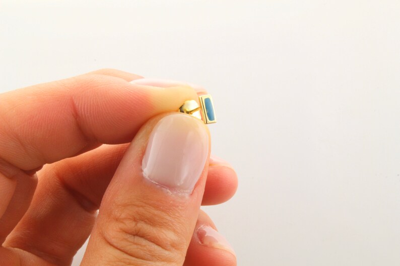 May include: Gold earring with a blue rectangular stone.