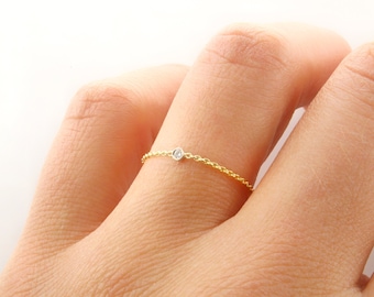 May include: A delicate gold chain ring with a single small diamond.