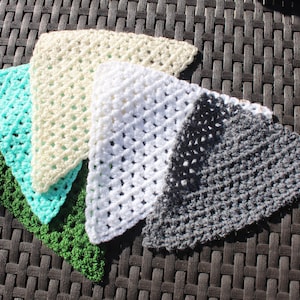 Peut inclure: Cinq chiffons triangulaires crochetés de couleurs variées : vert, turquoise, crème, blanc et gris. Les chiffons sont disposés en éventail, mettant en valeur leur tissage ouvert et ajouré. Les articles sont probablement faits à la main.
