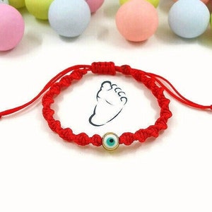 Peut inclure: Bracelet en cordon rouge avec un charme œil bleu maléfique. Le bracelet est noué et a un petit charme empreinte de pied.