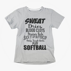 May include: Light gray t-shirt with black text. The text reads "SWEAT Dries BLOOD CLOTS Bruises Fade SUCK IT UP BUTTERCUP Only Tough Girls PLAY SOFTBALL". A casual tee for softball players.