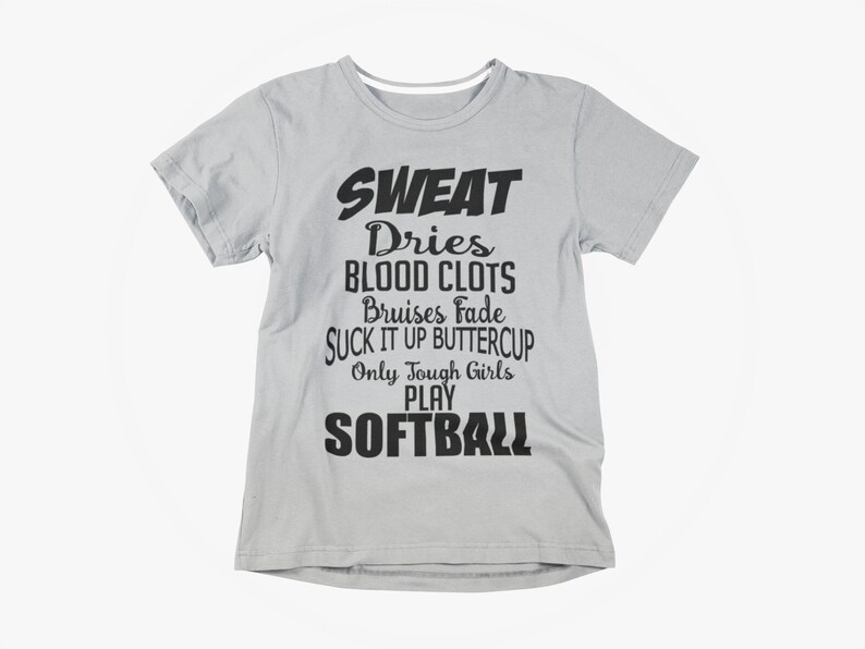 May include: Light gray t-shirt with black text. The text reads "SWEAT Dries BLOOD CLOTS Bruises Fade SUCK IT UP BUTTERCUP Only Tough Girls PLAY SOFTBALL". A casual tee for softball players.
