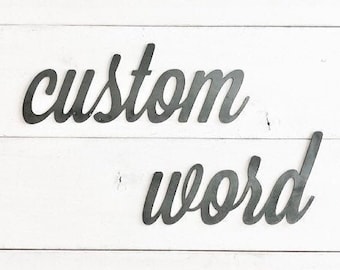 May include: Custom word sign made of metal with a white background. The sign is in a cursive font.