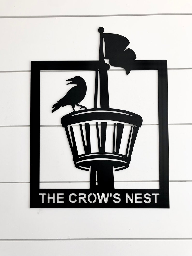 May include: Black metal sign with a crow perched on a tower with a flag. The sign reads "The Crow's Nest".