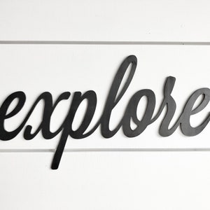 May include: Black metal wall decor with the word "explore" written in a cursive font.