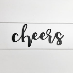 May include: Black metal wall decor with the word "cheers" written in a cursive font.