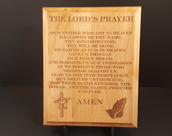 May include: A wooden plaque with the Lord's Prayer engraved in brown text. The plaque is on a small wooden stand. The text includes the words "Our Father who art in heaven, hallowed be thy name." and "Amen".