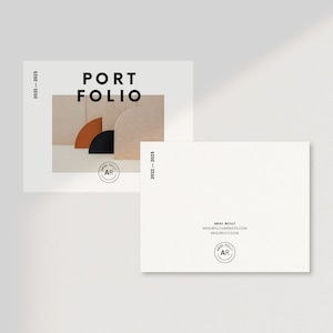 Puede incluir: Una tarjeta blanca con el texto "PORTFOLIO 2021 - 2022" en negro. La tarjeta presenta una foto de tres formas de medio c&iacute;rculo en marr&oacute;n, negro y beige. La tarjeta tambi&eacute;n incluye un peque&ntilde;o c&iacute;rculo con el texto "AR" en negro.