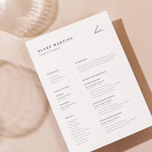 May include: A resume for Blake Martins, Interior Designer, printed on white paper. The resume includes sections for contact information, education, skills, summary, and work experience. The background is a light beige color.