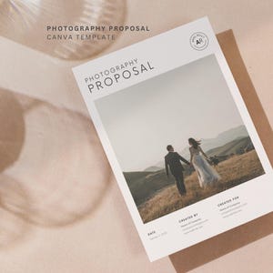 May include: A white Photography Proposal Canva Template with a photo of a couple walking in a field. The text "PHOTOGRAPHY PROPOSAL" is at the top, with additional details below. The template is on a brown envelope, with a soft, neutral background.