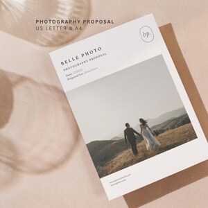 Op de afbeelding: Een fotografievoorstel document met de tekst "PHOTOGRAPHY PROPOSAL US LETTER & A4" en "BELLE PHOTO PHOTOGRAPHY PROPOSAL". Het document bevat een foto van een stel dat in een veld loopt. Het document ligt op een bruine envelop.