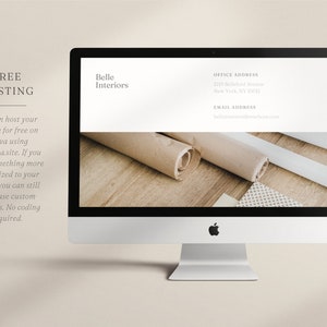 May include: A silver iMac computer displays a website mockup for "Belle Interiors." The screen shows the company name, address, and email. The image also includes text about free website hosting and custom domains. Rolls of paper and design samples are visible.