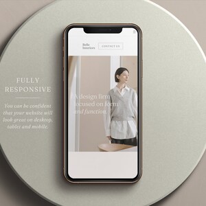 May include: A smartphone with a gold frame displays a website mockup for "Belle Interiors." The website features a woman in a neutral-toned outfit. Text on the phone reads "A design firm focused on form and function." The background includes the text "FULLY RESPONSIVE."