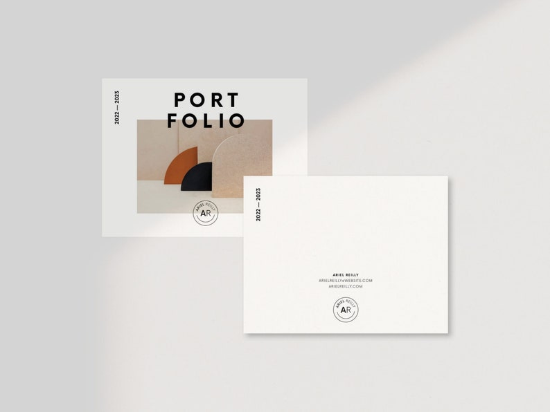 Puede incluir: Una tarjeta blanca con el texto "PORTFOLIO 2021 - 2022" en negro. La tarjeta presenta una foto de tres formas de medio c&iacute;rculo en marr&oacute;n, negro y beige. La tarjeta tambi&eacute;n incluye un peque&ntilde;o c&iacute;rculo con el texto "AR" en negro.