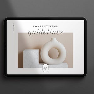 May include: A digital tablet displaying a company branding guide with the text "COMPANY NAME guidelines" and a photo of a white ceramic vase with a ring-shaped opening on a beige background. The text "bg." is also visible on the screen.