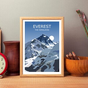 May include: A framed print of a mountain range with the text "EVEREST THE HIMALAYAS" at the top. The mountain range is depicted in shades of blue and white, with a white moon in the sky.