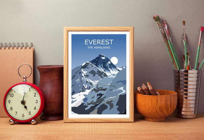 May include: A framed print of a mountain range with the text "EVEREST THE HIMALAYAS" at the top. The mountain range is depicted in shades of blue and white, with a white moon in the sky.