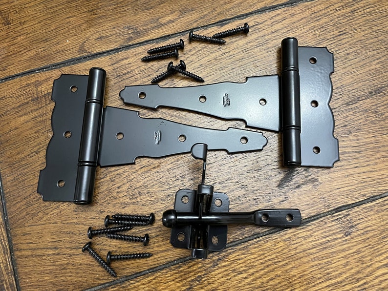 May include: Black metal gate hardware set with two hinges, a latch, and screws. The hinges have a decorative design and the latch has a round knob.