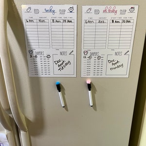 May include: Two white refrigerator magnets with black writing. Each magnet has a section for "Feed", "Sleep", "Diapers", and "Notes". One magnet has the name "Rocky" written on it and the other has the name "Oh Baby". Both magnets have a section for recording times and amounts. The "Notes" section on the "Rocky" magnet has the text "Doc Appt. Tuesday" written on it. The "Notes" section on the "Oh Baby" magnet has the text "Doc Appt. Monday" written on it.