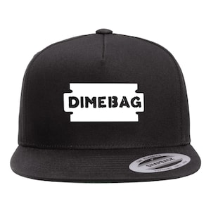 May include: Black snapback hat with the word "DIMEBAG" in bold white letters inside a white rectangle. The hat has a flat brim and a classic snap closure. The hat is a classic style.