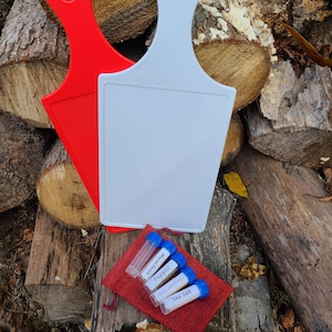 Puede incluir: Dos tablas de cortar blancas con mangos rojos, una con la palabra "Pepper" escrita en ella. Una bolsa roja con cuatro pequeños viales de vidrio que contienen especias etiquetadas como "Sal marina", "Pimienta molida", "Pimienta" y "Cebolla picada".