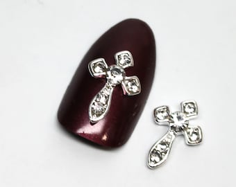 May include: Two silver cross nail charms with clear rhinestones. The charms are small and delicate, perfect for adding a touch of sparkle to your nails.
