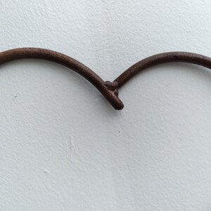 May include: A rusty metal heart-shaped frame, with a smooth, white background.