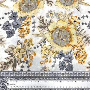 K&ouml;nnte beinhalten: Wei&szlig;er Stoff mit einem floralen Muster mit gelben, orangefarbenen und grauen Blumen. Der Stoff hat einen grauen Rand mit einem sich wiederholenden Muster.