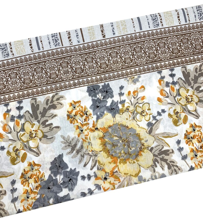 K&ouml;nnte beinhalten: Wei&szlig;er Stoff mit einem floralen Muster in Graut&ouml;nen, Gelb und Braun. Der Stoff hat einen Rand mit einem sich wiederholenden Muster.