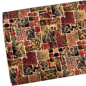 May include: A fabric with a patchwork design featuring brown, red, and beige squares with a leaf pattern. The fabric has a textured surface.