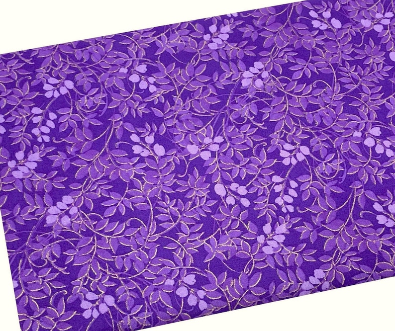 May include: Purple fabric with a repeating pattern of gold and purple leaves. The leaves are arranged in a vine-like pattern.