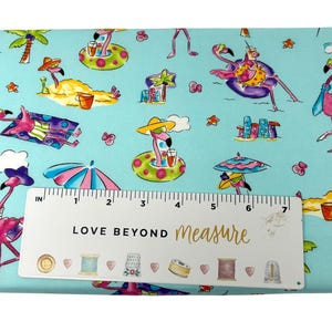 May include: A light blue fabric with a repeating pattern of pink flamingos in sunglasses and hats, enjoying tropical drinks and lounging on the beach. The fabric also features palm trees, umbrellas, and the text "LOVE BEYOND measure".
