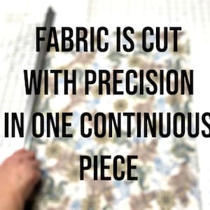 K&ouml;nnte beinhalten: Nahaufnahme von Stoff, der mit einem Lineal geschnitten wird. Der Text "FABRIC IS CUT WITH PRECISION IN ONE CONTINUOUS PIECE" ist auf dem Bild zu sehen.