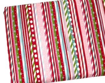 Può includere: Un pezzo di tessuto piegato con un motivo a righe verticali ripetute in rosso, rosa chiaro, verde e azzurro. Il design include linee sottili, righe diagonali e file di fiocchi di neve bianchi e motivi a pois circolari su tutto il tessuto.