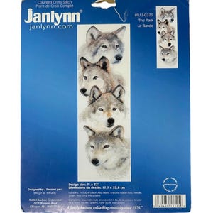 May include: A counted cross stitch pattern featuring five wolf faces in shades of gray. The pattern is titled "The Pack" and is from Janlynn.com.