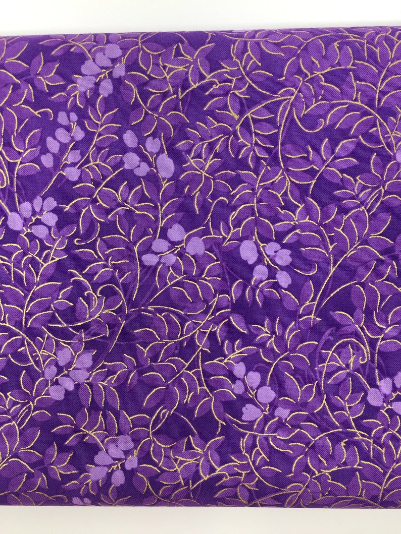 May include: Purple fabric with a gold leaf pattern. The leaves are outlined in gold and the background is a deep purple.