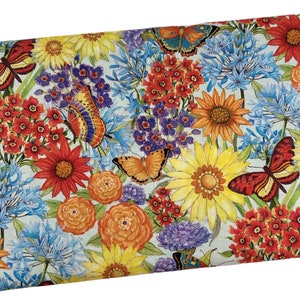May include: A colorful fabric with a floral pattern featuring butterflies, sunflowers, and other flowers in shades of red, yellow, blue, and purple.