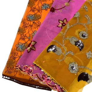 May include: Three sheer fabric panels in orange, pink, and mustard yellow. Each panel features intricate floral embroidery with metallic thread, sequins, and beads. The edges are finished with scalloped borders adorned with dense sequin embellishments.